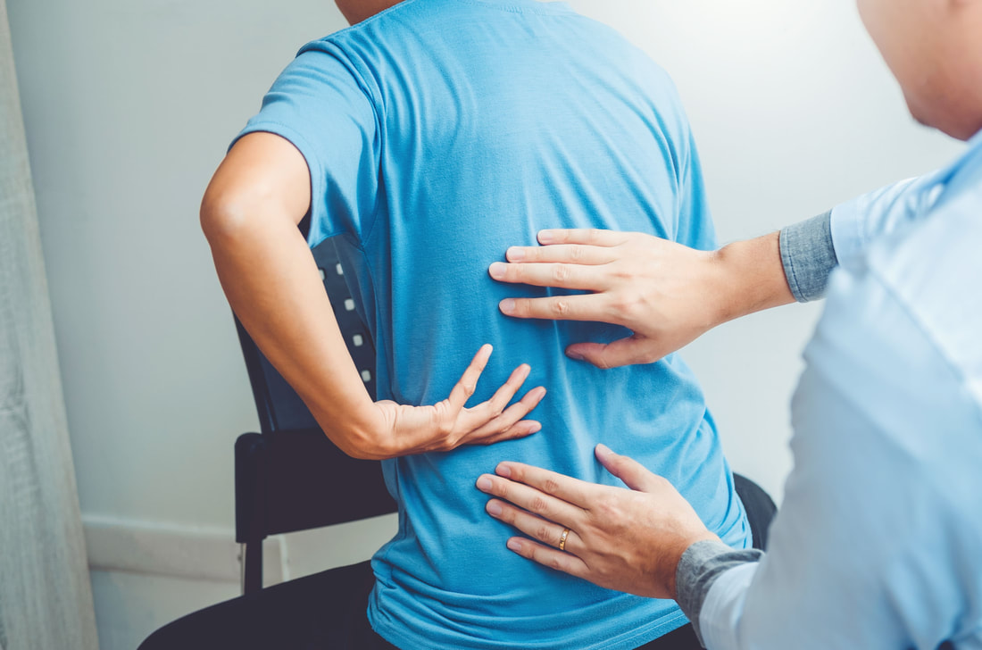 Physical Therapist evaluating man with lower back pain in blue shirt